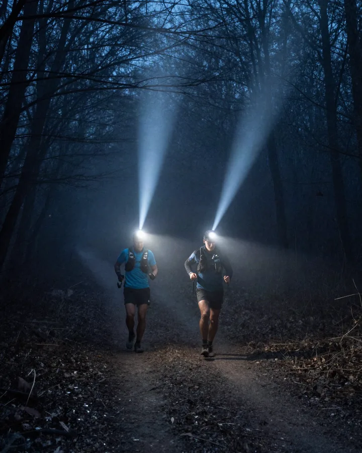 Due corridori con lampade frontali su un sentiero nel bosco di notte