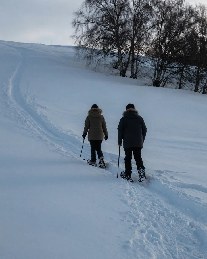 Due persone con le ciaspole su un altopiano innevato al tramonto