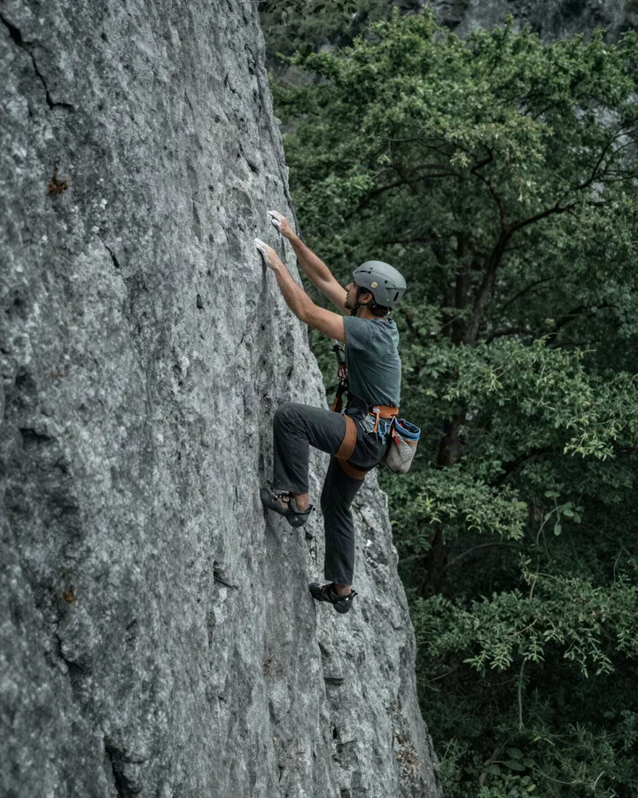 Arrampicatore su una parete di calcare in una gola boscosa